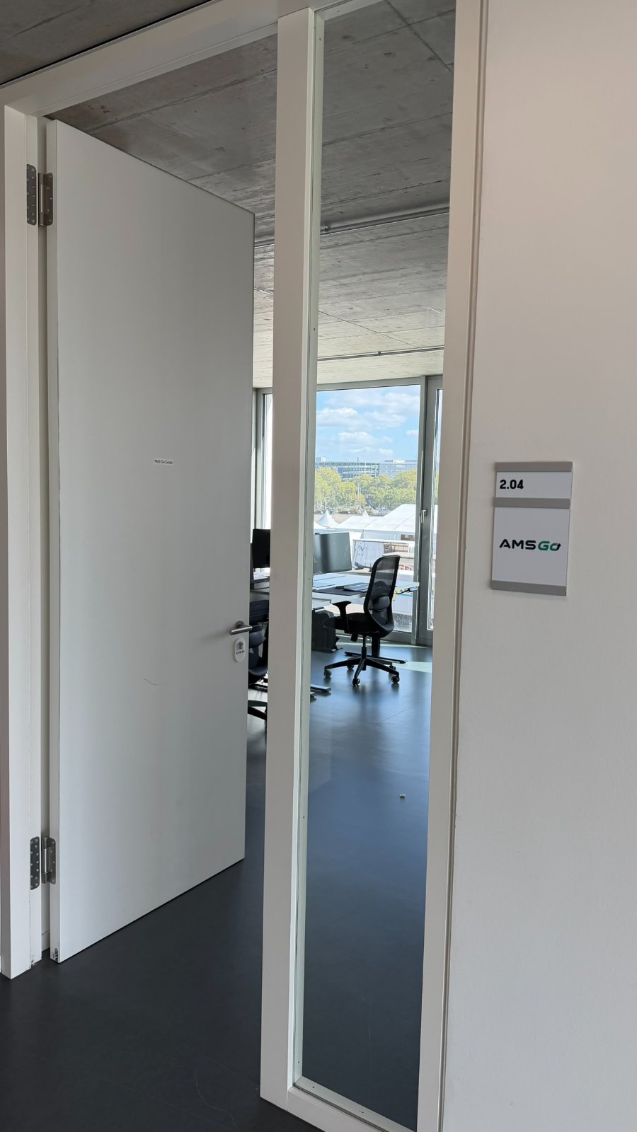 Door sign with the AMS Go logo at room 2.04 at FUX